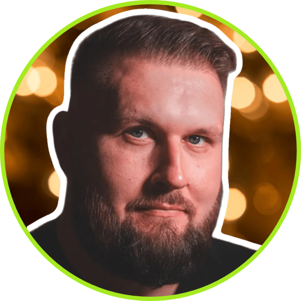 projektowanie stron www Brodaty mężczyzna z krótkimi włosami patrzy w kamerę, otoczony jasnozielonym okręgiem. Tło zawiera rozmyte, ciepłe światła, przypominające profesjonalną sesję fotograficzną. fotografia filmowanie augustów